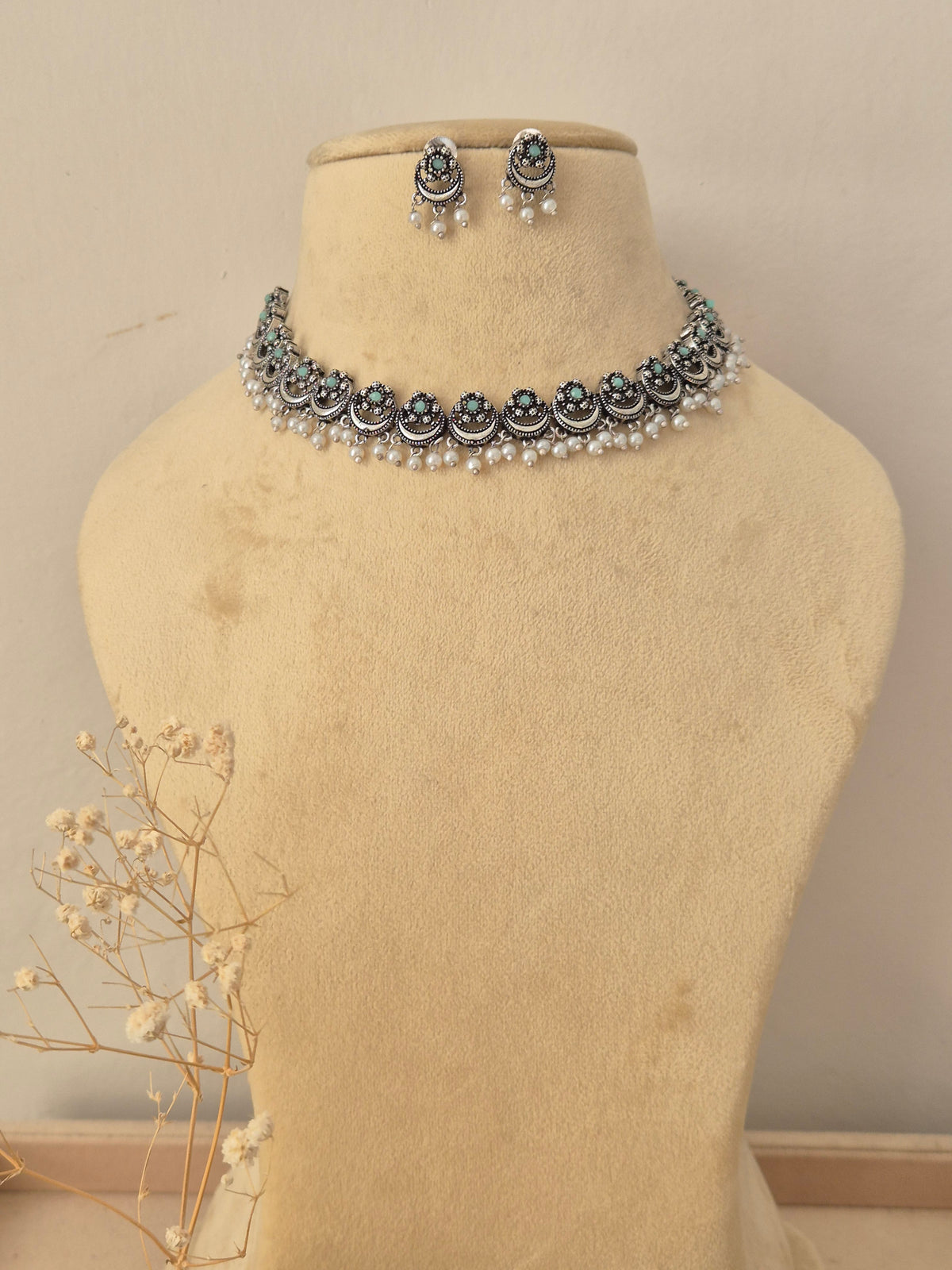 Oxidized silver choker necklace featuring green stone accents and dangling pearl beads, with matching circular stud earrings by naitri.in