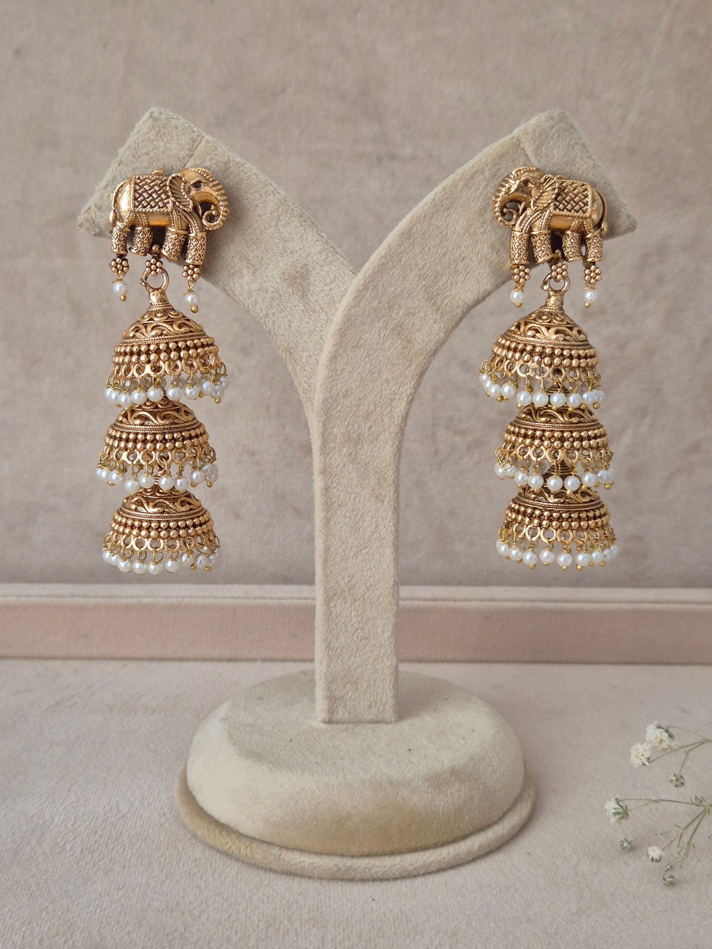 Festive antique gold ethnic earrings featuring carved temple motifs and pearl drop clusters for wedding and traditional wear. Antique gold traditional Indian dangle earrings with goddess motif, colorful stone accents, and pearl drops by naitri.in