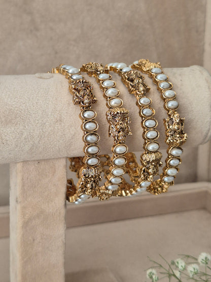 Antique gold bangles with delicate faux pearl embellishments and detailed traditional Indian craftwork by naitri.in