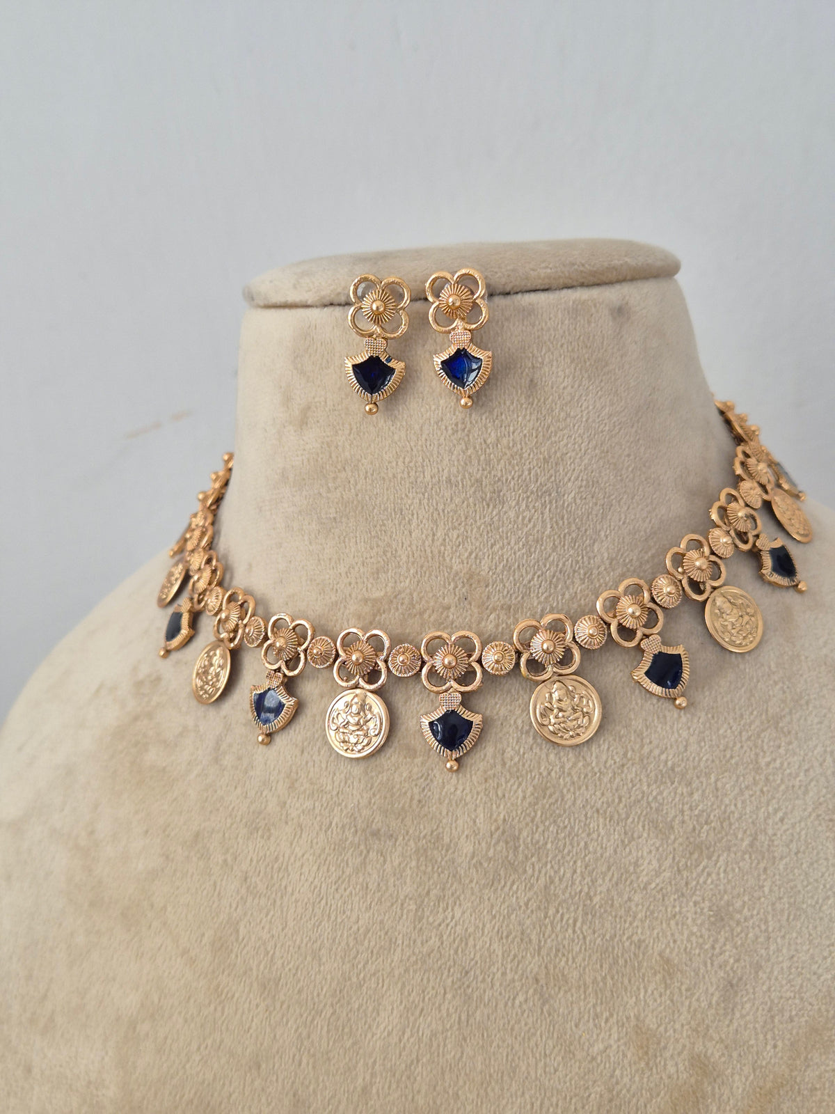 Ornate Designer Charm Necklace and Studs presented on a display bust, emphasizing the refined pendant design, rich metallic finish, and timeless appeal for modern ethnic wear by Naitri.in