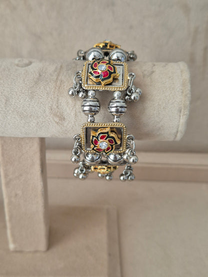 Dual-toned gold and silver Apeksha bangle with floral enamel detailing and hanging ghungroo beads by naitri.in