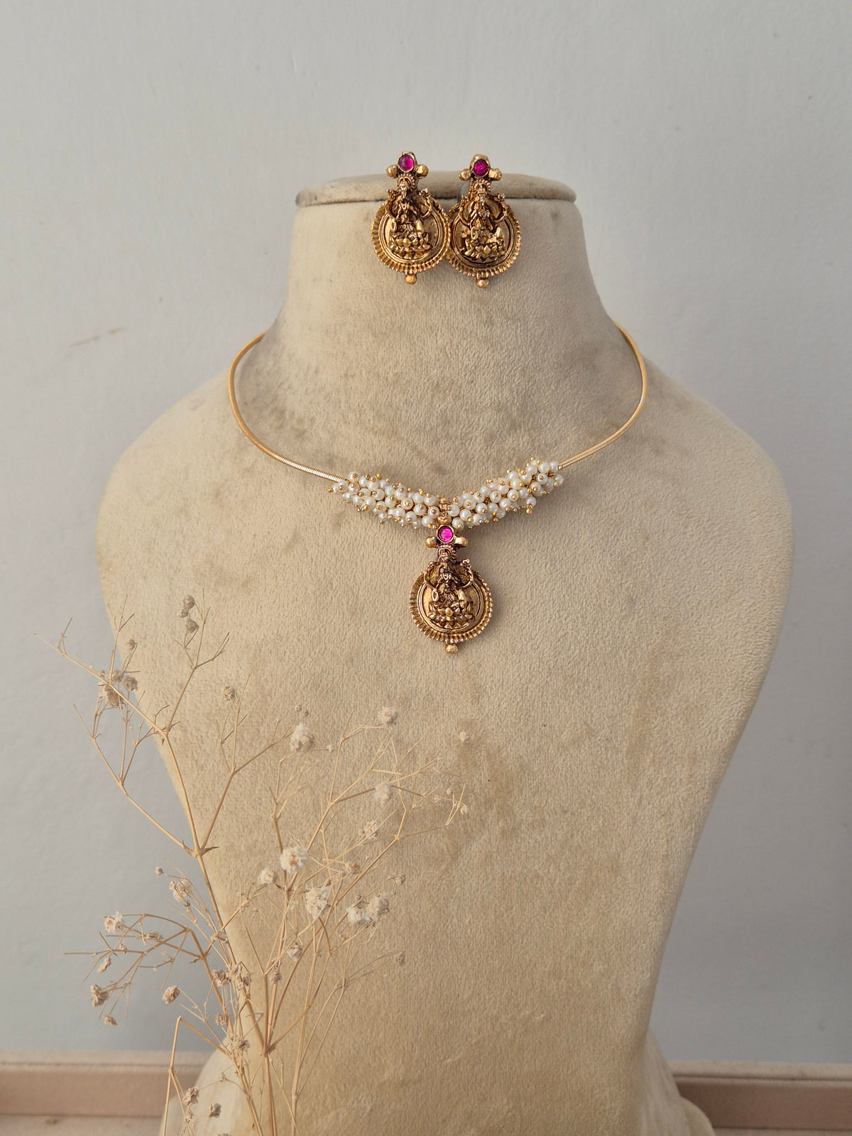 Traditional gold-plated choker necklace set featuring a detailed pendant and delicate beadwork, displayed on a mannequin with matching stud earrings by Naitri.in