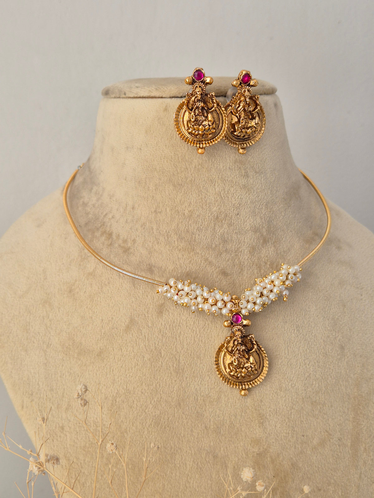Ornate gold-toned fashion jewelry set with a detailed pendant design and matching earrings for ethnic wear by Naitri.in