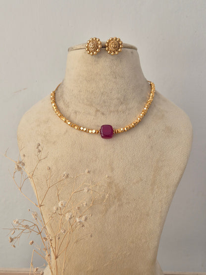 Traditional gold-plated choker necklace set featuring a vibrant pink center stone, displayed on a mannequin with matching stud earrings by Naitri.in