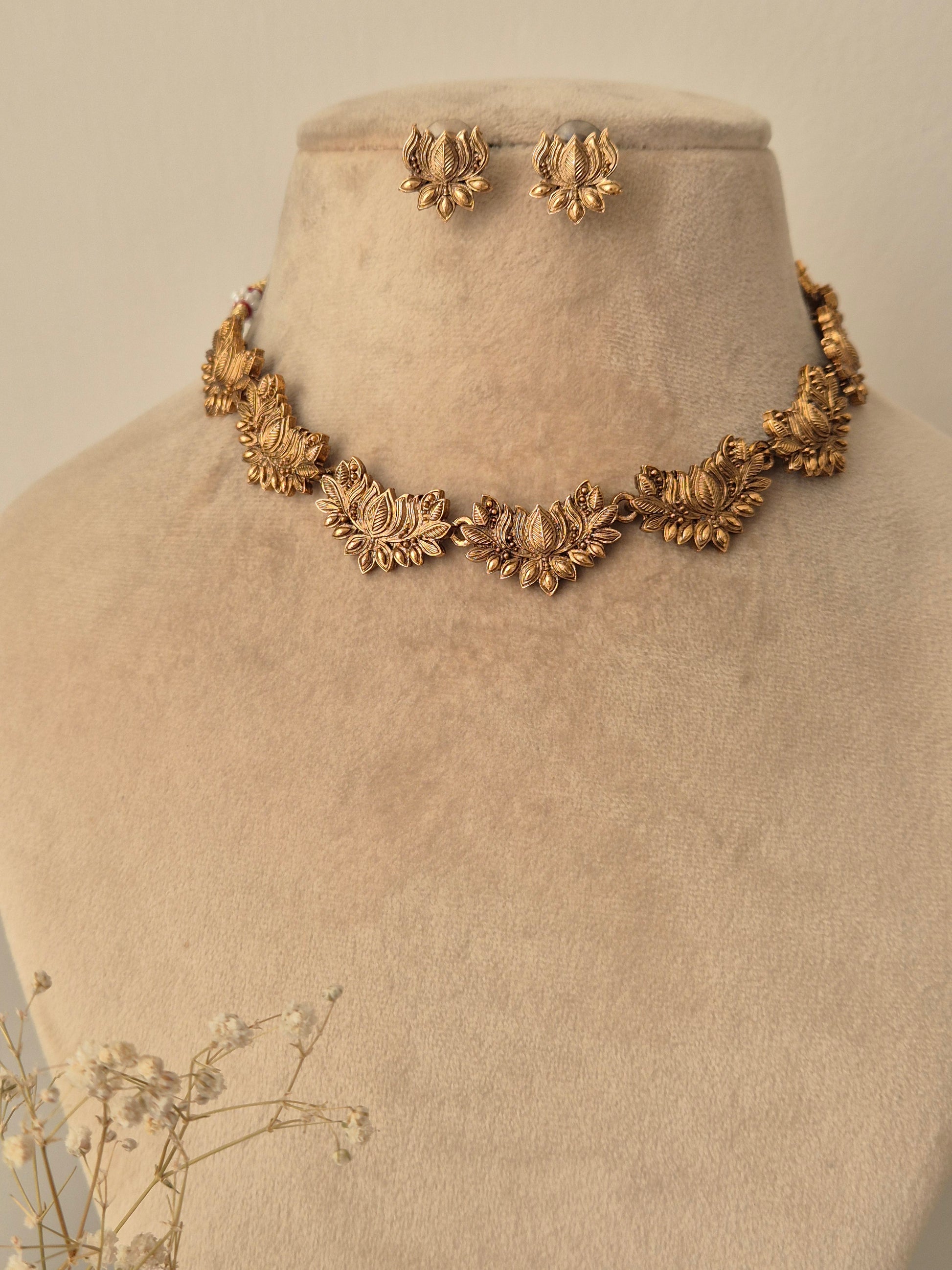 close-up of the Harnoor Necklace Set featuring a golden brass chain with intricate floral elements, accompanied by matching floral stud earrings by naitri.in