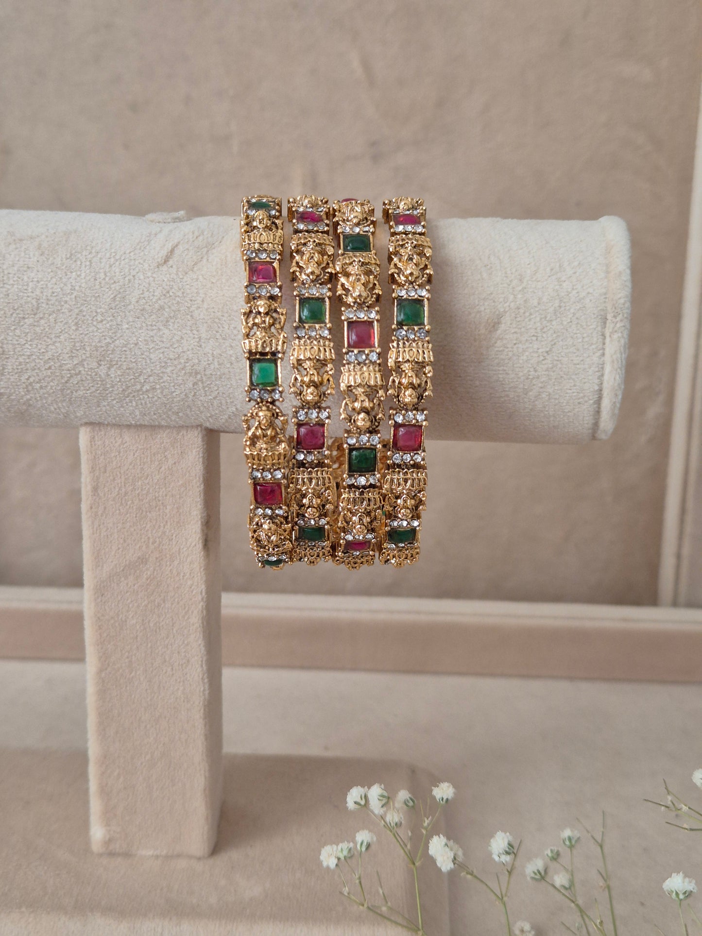 Set of four traditional gold-toned bangles with detailed engraving and red and green stones by naitri.in