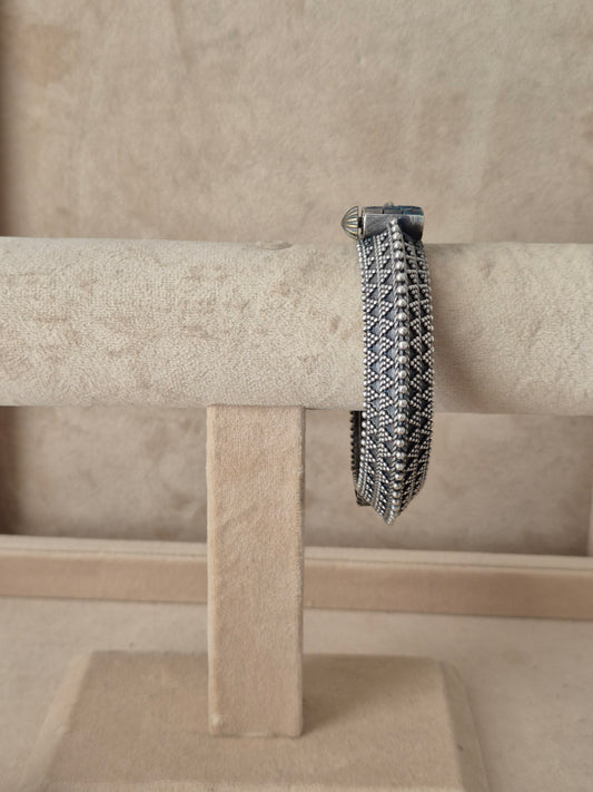 Intricate silver oxidized Ashoki bangle with a textured geometric diamond pattern by naitri.in 
