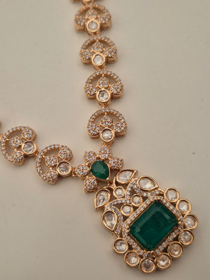 Alloy necklace set featuring floral crystal patterns and a central emerald-cut green stone pendant by naitri.in