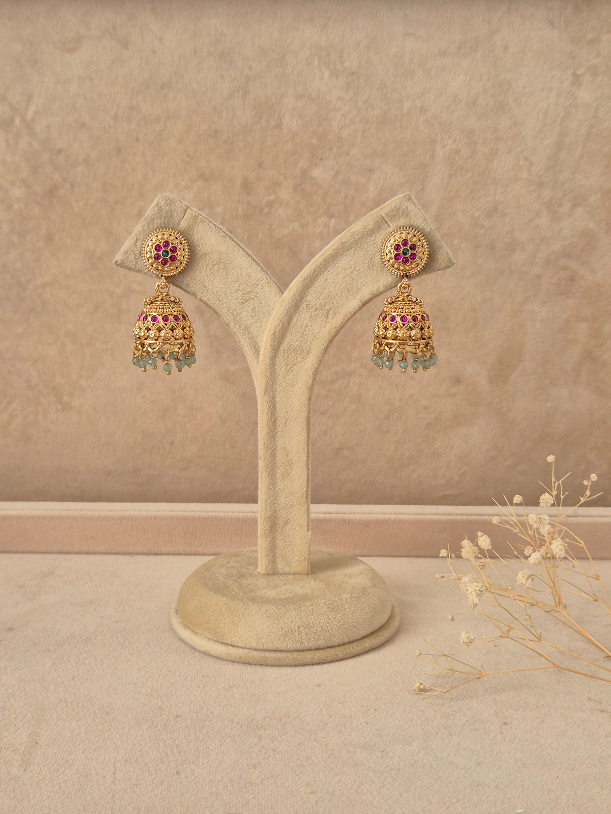 Babli handcrafted gold-finish jhumka earrings with ruby and green stone accents by naitri.in