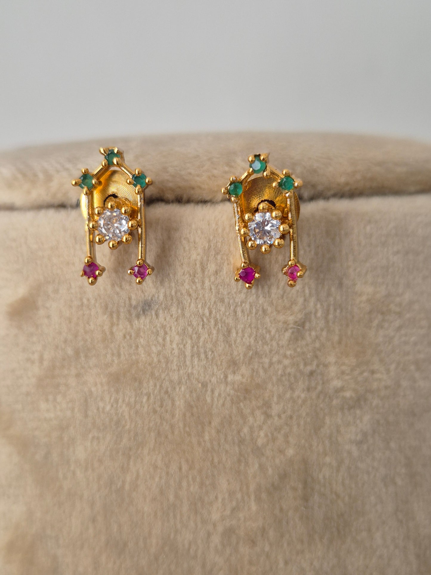 Minimalist gold-toned earring  with dangling teardrop motifs in vibrant pinkish-red and sparkling clear crystals, by naitri.in