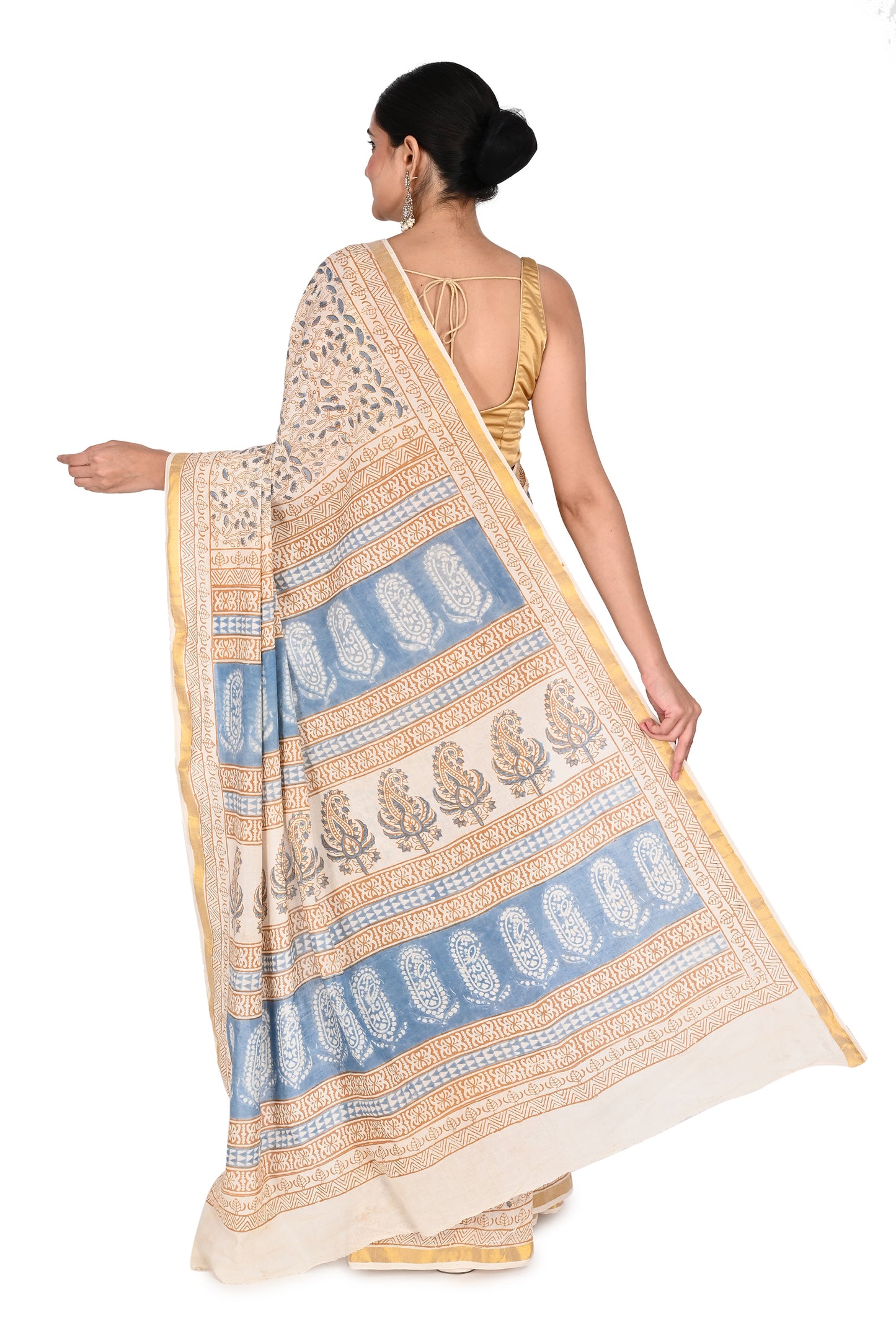 Beige and white Ambika cotton saree paired with a gold sleeveless blouse and silver earrings for a modern ethnic look by naitri.in