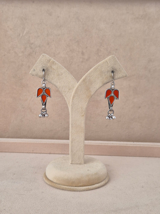 A pair of silver-toned dangle earrings with red glass in a leaf design with small silver beads by naitri.in
