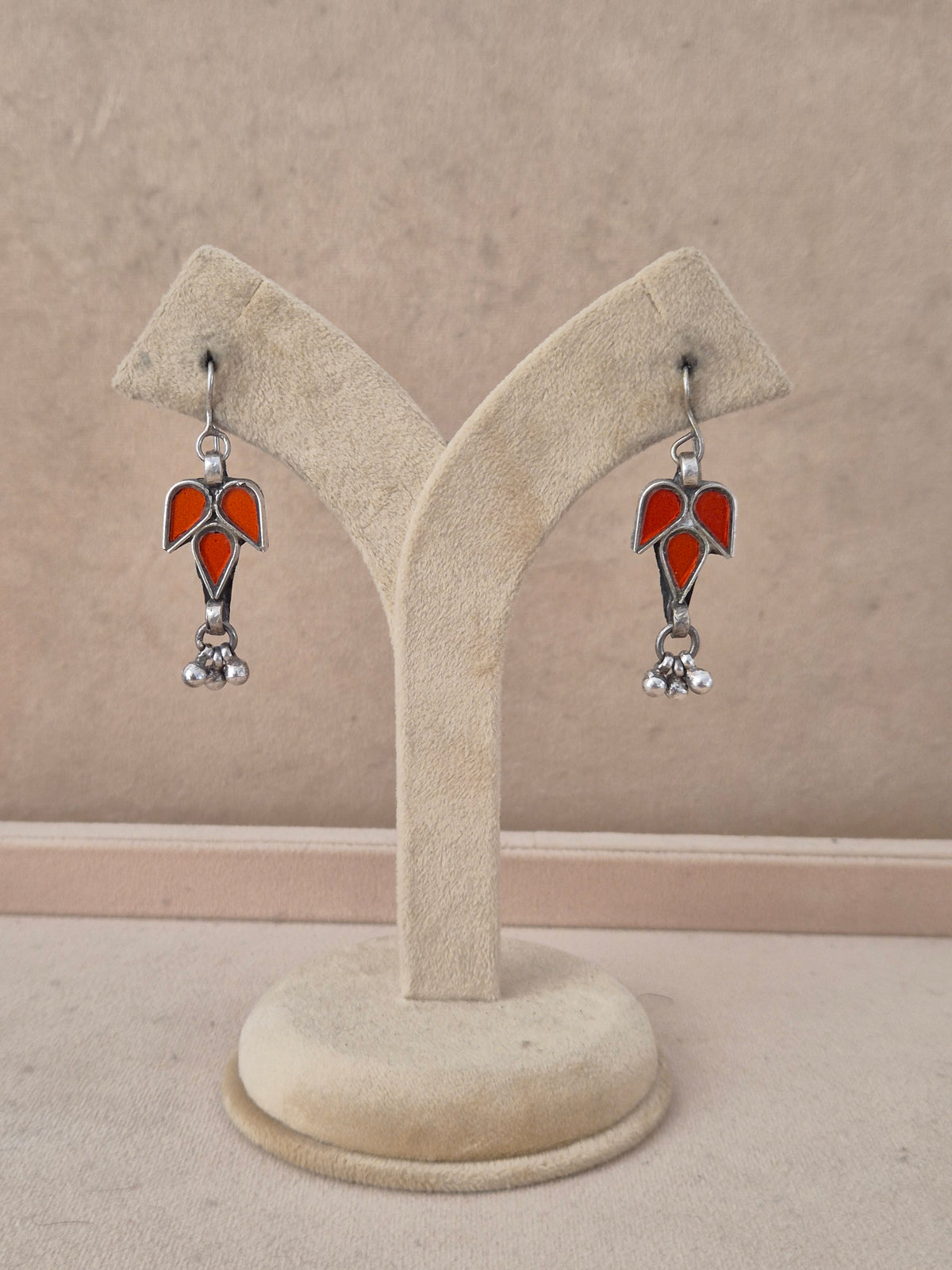 Pair of red leaf-shaped glass drop earrings with silver bead detail. Bala red glass dangle earrings with silver embellishments by naitri.in