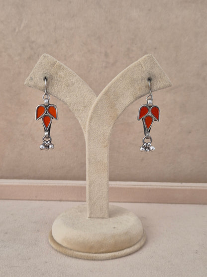 Pair of red leaf-shaped glass drop earrings with silver bead detail. Bala red glass dangle earrings with silver embellishments by naitri.in