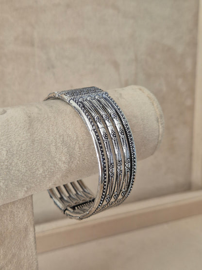 Wide oxidized silver Basanti cuff bangle with vertical cutout panels and geometric engravings  by naitri.in