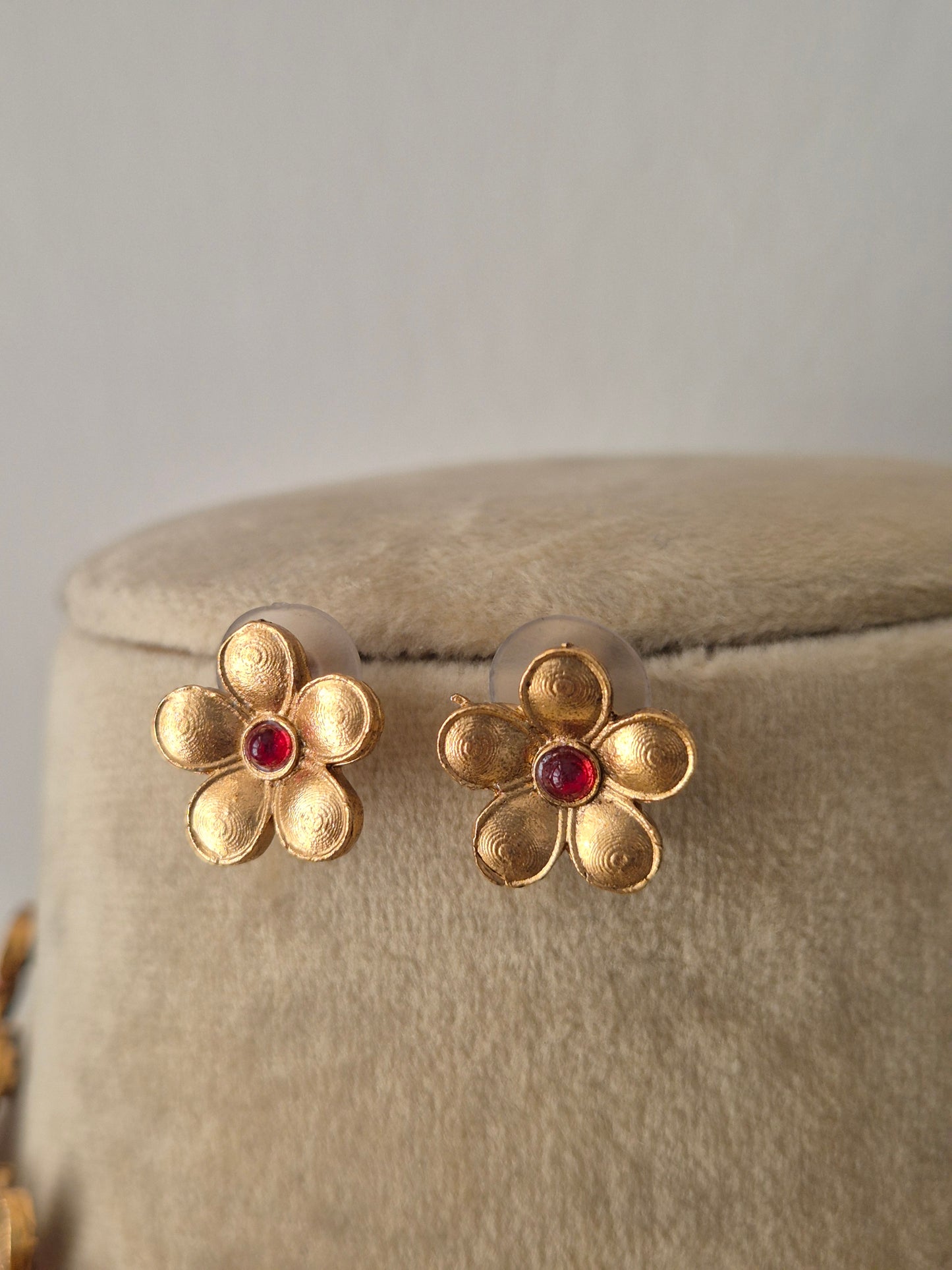 Gold-plated floral earrngs with delicate floral motifs and pinkish-red stone centers, by naitri.in