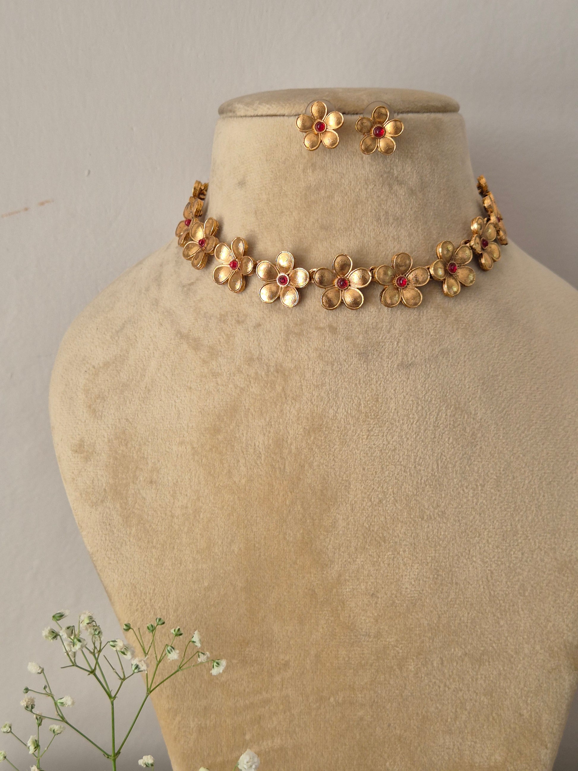 Elegant traditional gold-toned ethnic choker jewelry set with detailed metalwork flowers, showcased by naitriin