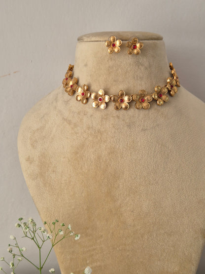 Elegant traditional gold-toned ethnic choker jewelry set with detailed metalwork flowers, showcased by naitriin