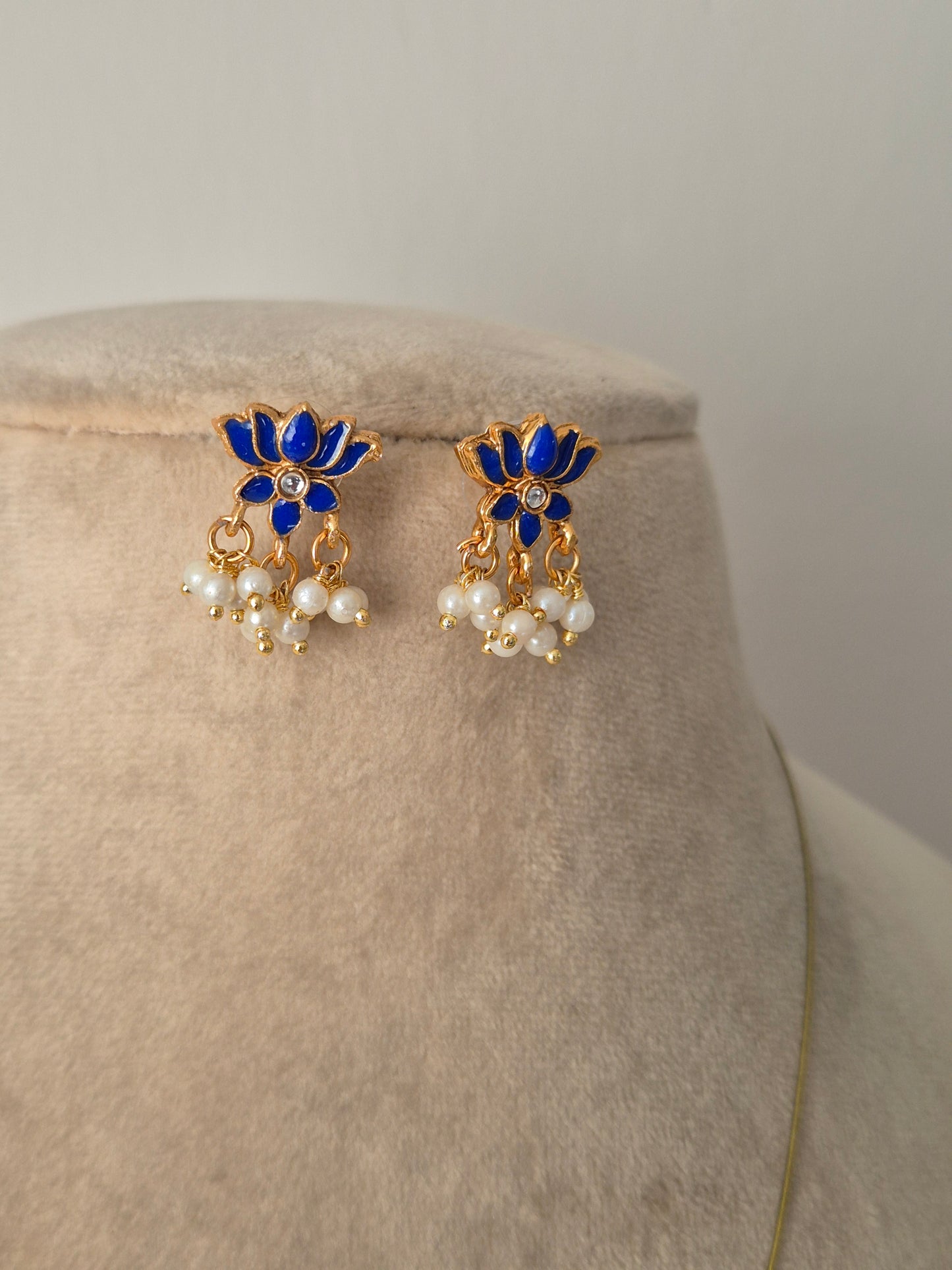 Pair of earrings with blue and gold lotus design a small stone in middle of flower and some pearls hanging from flower by naitri.in