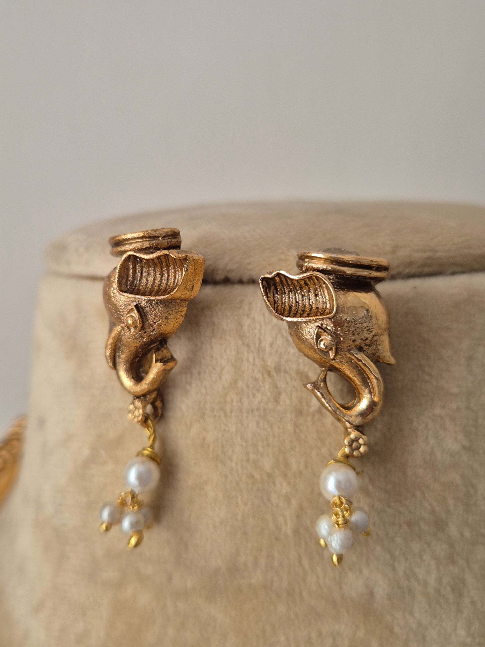 Golden ethnic earrings with delicate white pearl hangings by naitri.in
