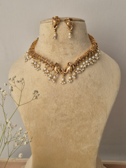 Bhagrati necklace set featuring an intricate gold choker adorned with white pearl drops and matching gold-plated drop earrings by naitri.in
