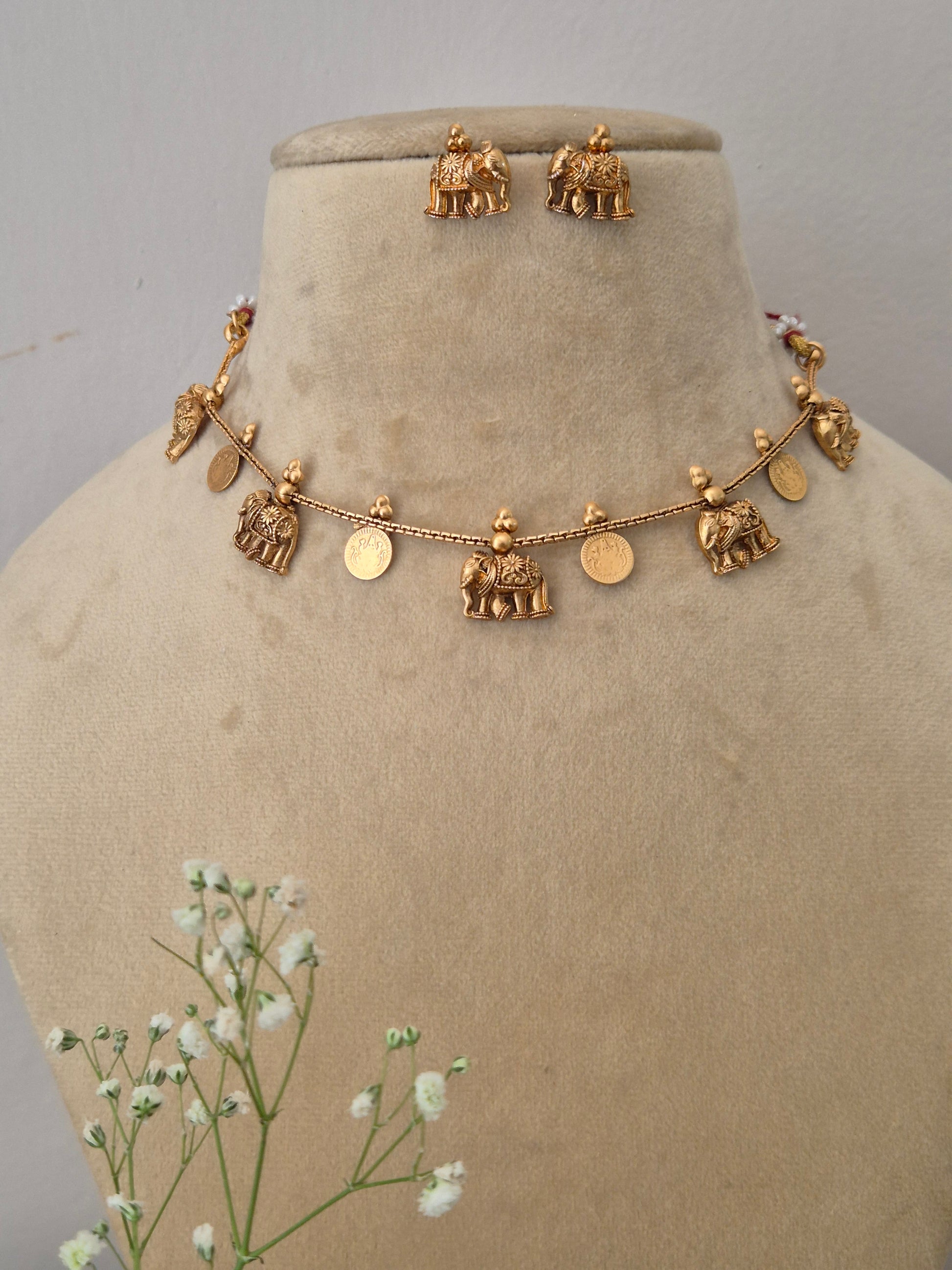 Fine craftsmanship golden ethnic necklace set with intricate dangling design elements Traditional gold-toned choker necklace  with hanging coin motifs and matching earrings by naitri.in