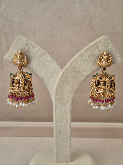 Traditional gold-toned peacock design Jhumka earrings with pink gemstones and white pearl drops by naitri.in