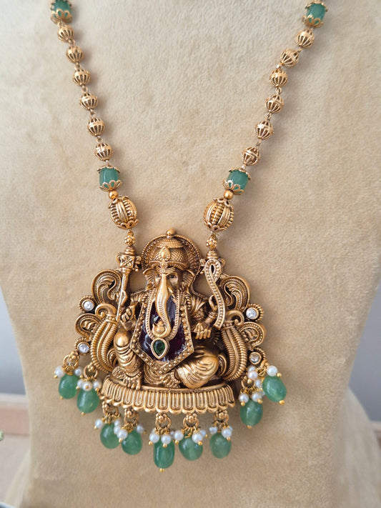 Modern Indian ethnic imitation jewelry set including a textured golden brass alloy long-chain necklace, a large detailed Ganesha motif pendant with green bead drops, by naitri.in