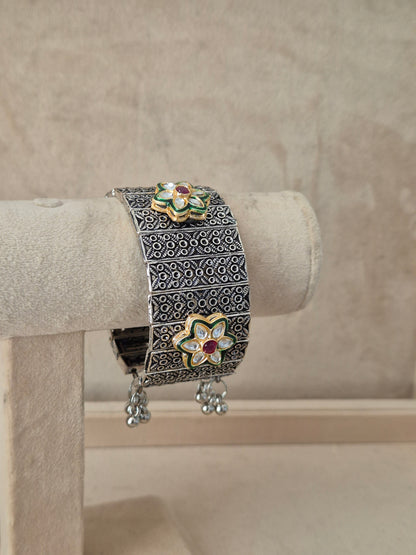 Bohemian-style wide silver-plated statement cuff bangle featuring mesh-like open-work textures and delicate hanging bell charms by naitri.in