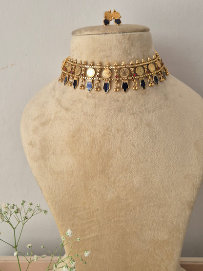 A gold-plated choker necklace featuring a row of alternating blue and dark gemstone charms by naitri.in