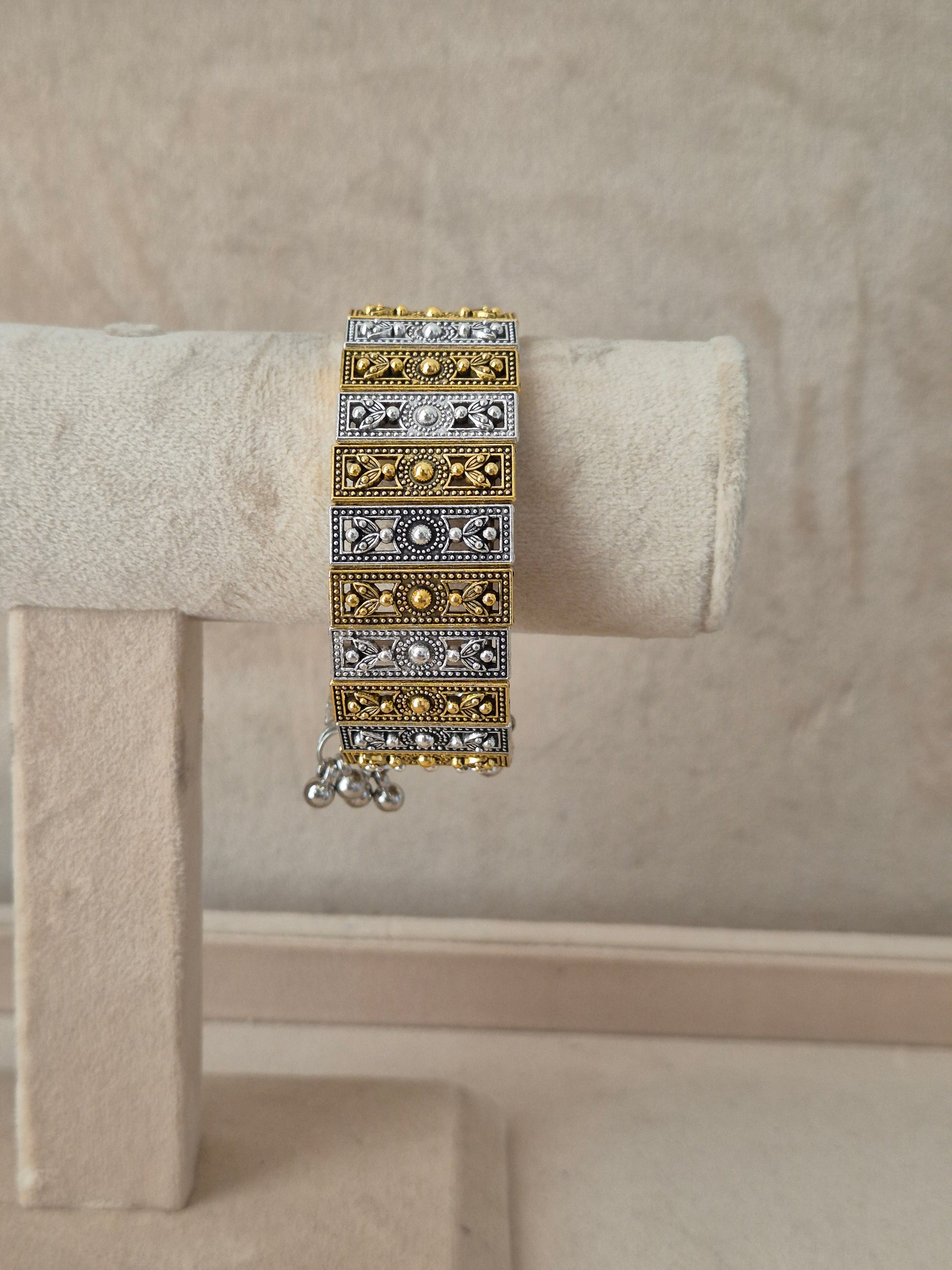 Dual-tone Binita bangle bracelet featuring an alternating pattern of textured gold and oxidized silver rectangular blocks with tiny gold bead borders  by  naitri.in