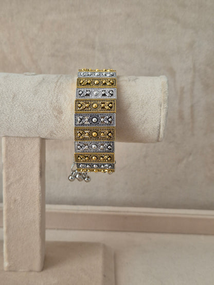 Dual-tone Binita bangle bracelet featuring an alternating pattern of textured gold and oxidized silver rectangular blocks with tiny gold bead borders  by  naitri.in