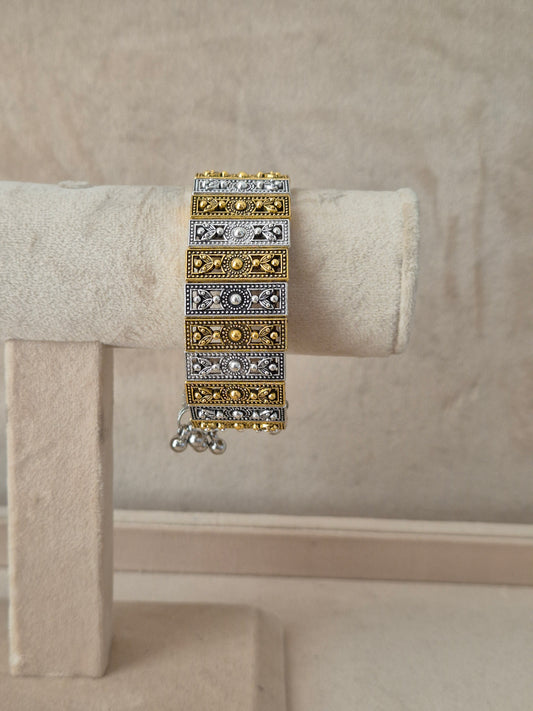 Dual-tone Binita bangle bracelet featuring an alternating pattern of textured gold and oxidized silver rectangular blocks with tiny gold bead borders  by  naitri.in