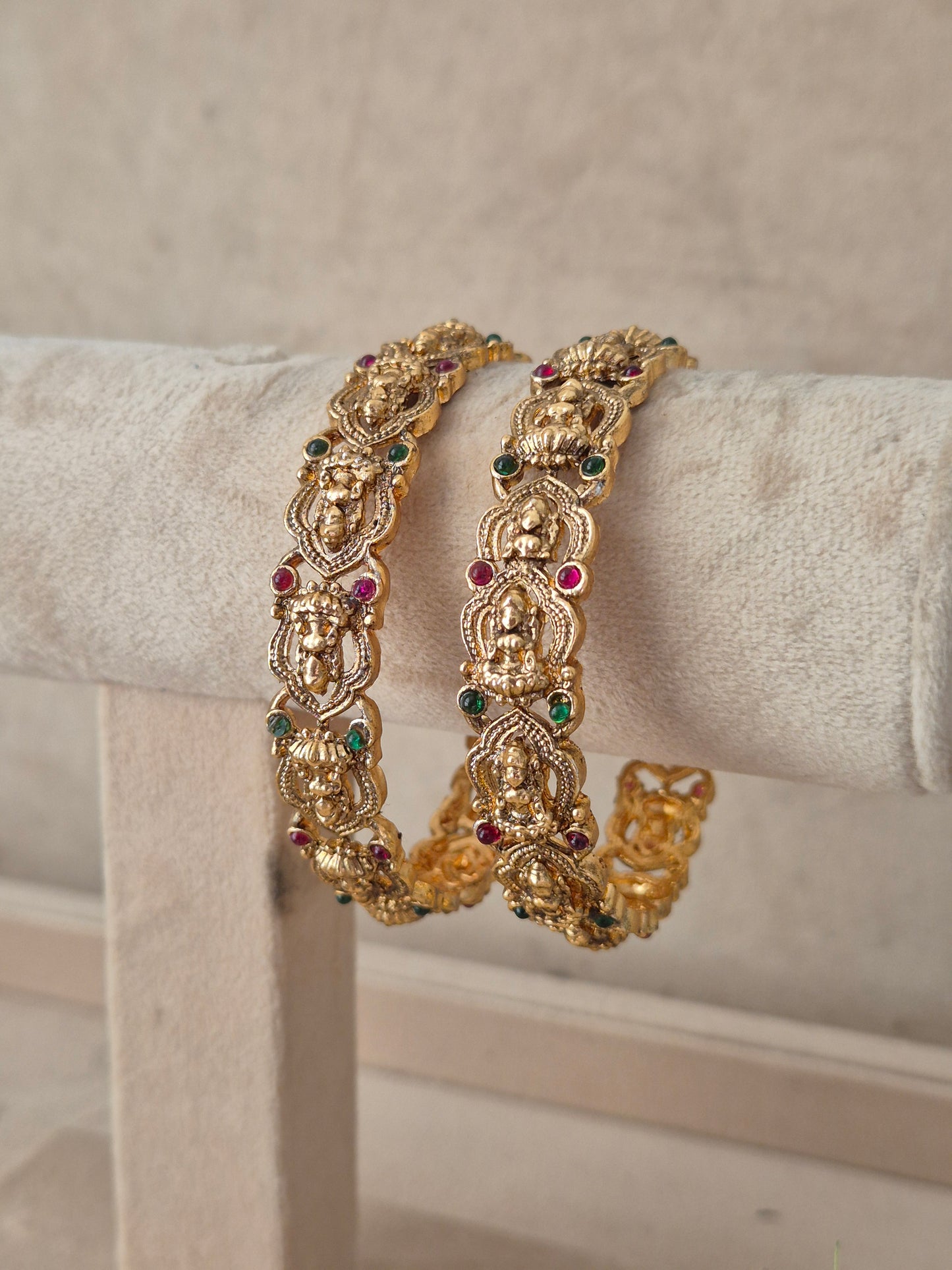 Two gold-toned ornate bangles with small multicolored stone accents, by naitri.in