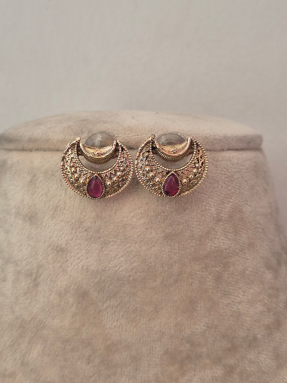 Delicate gold crescent-shaped earrings with red stone accents by naitri.in