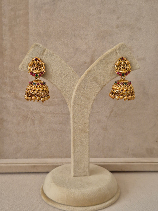 Traditional gold-toned  earrings featuring goddess Lakshmi motifs on the studs, accented with red and green gemstones and gold bead drops by naitri.in