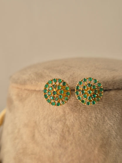 a handcrafted brass alloy earrings with a polished golden finish and small green circular gemstones by naitri.in