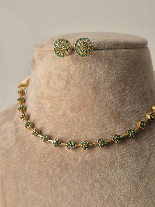 Close-up of the Champa Necklace Set, a handcrafted brass alloy jewelry set with a polished golden finish and small green circular gemstones by naitri.in