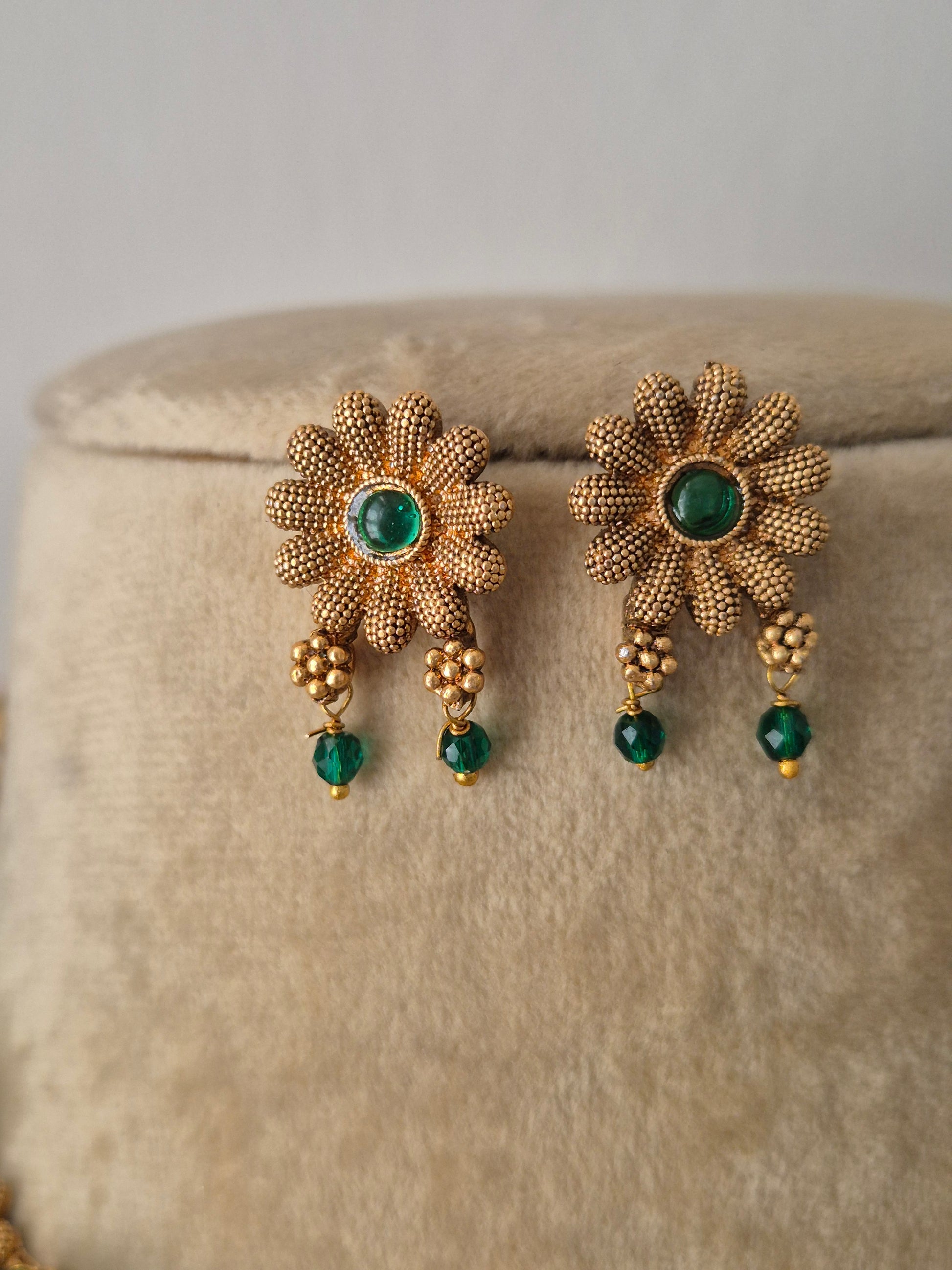 gold plated earring with floral design and green stone in the middle of flower and green hanging by naitri.in