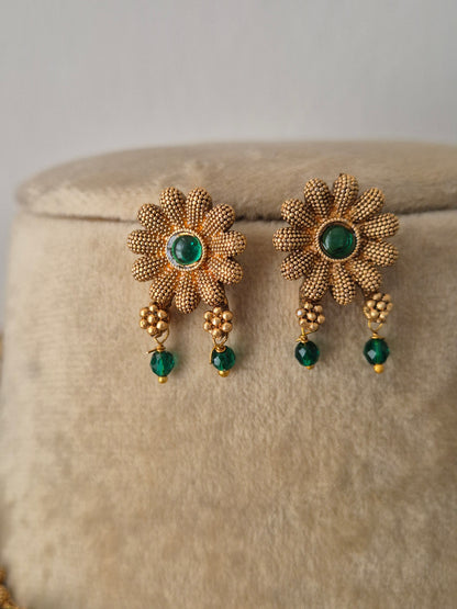 gold plated earring with floral design and green stone in the middle of flower and green hanging by naitri.in
