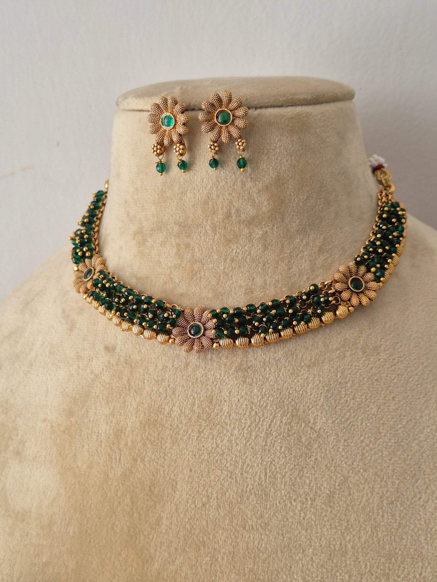 Gold-plated strand choker necklace with emerald green beads and matching flower stud earrings by naitri.in