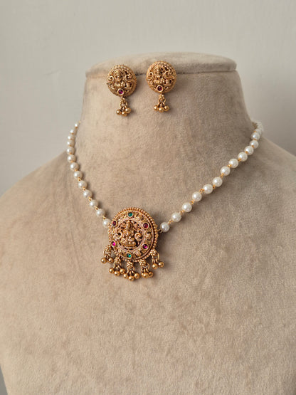 Set of gold jewelry with pearls single chain Antique gold-plated choker necklace featuring a central Goddess Lakshmi motif, hanging golden beads drops by naitri.in
