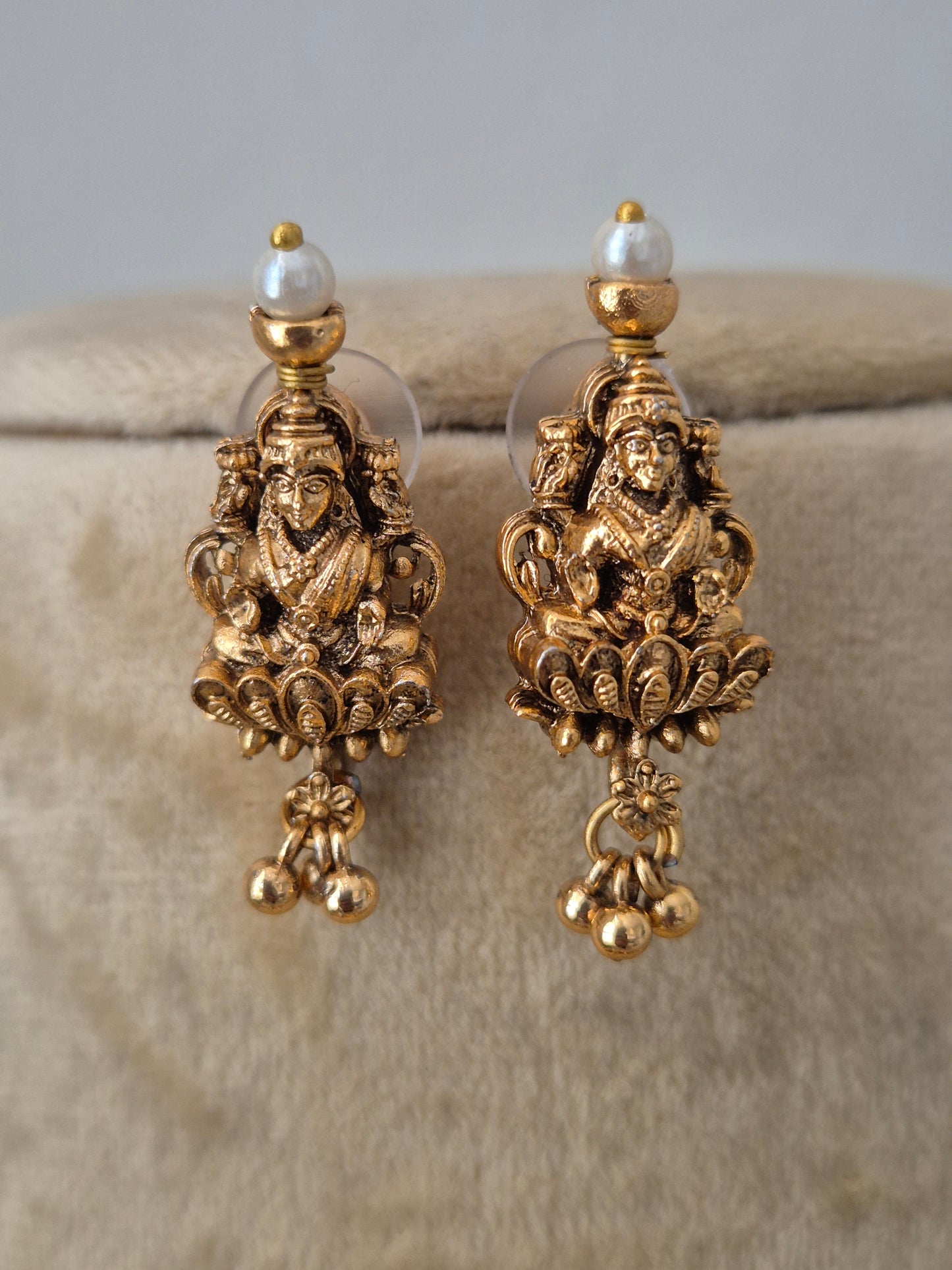 A pair of ornate gold-toned dangle earrings with intricate filigree detailing and small pearl-like beads, by naitri.in