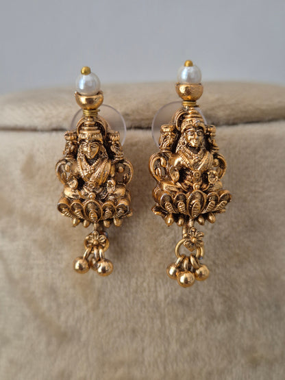 A pair of ornate gold-toned dangle earrings with intricate filigree detailing and small pearl-like beads, by naitri.in