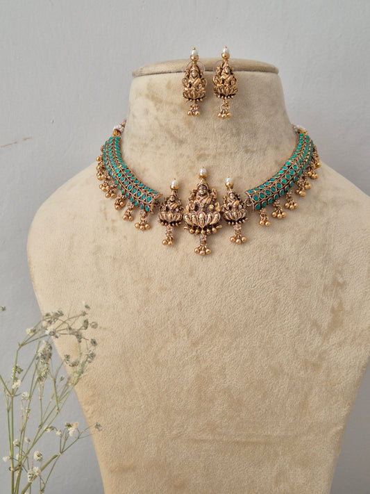 A traditional Indian jewelry set featuring a necklace, matching earrings, and a headband, the jewelry is made of gold-plated metal with turquoise blue stones and small white pearl accents by naitri.in