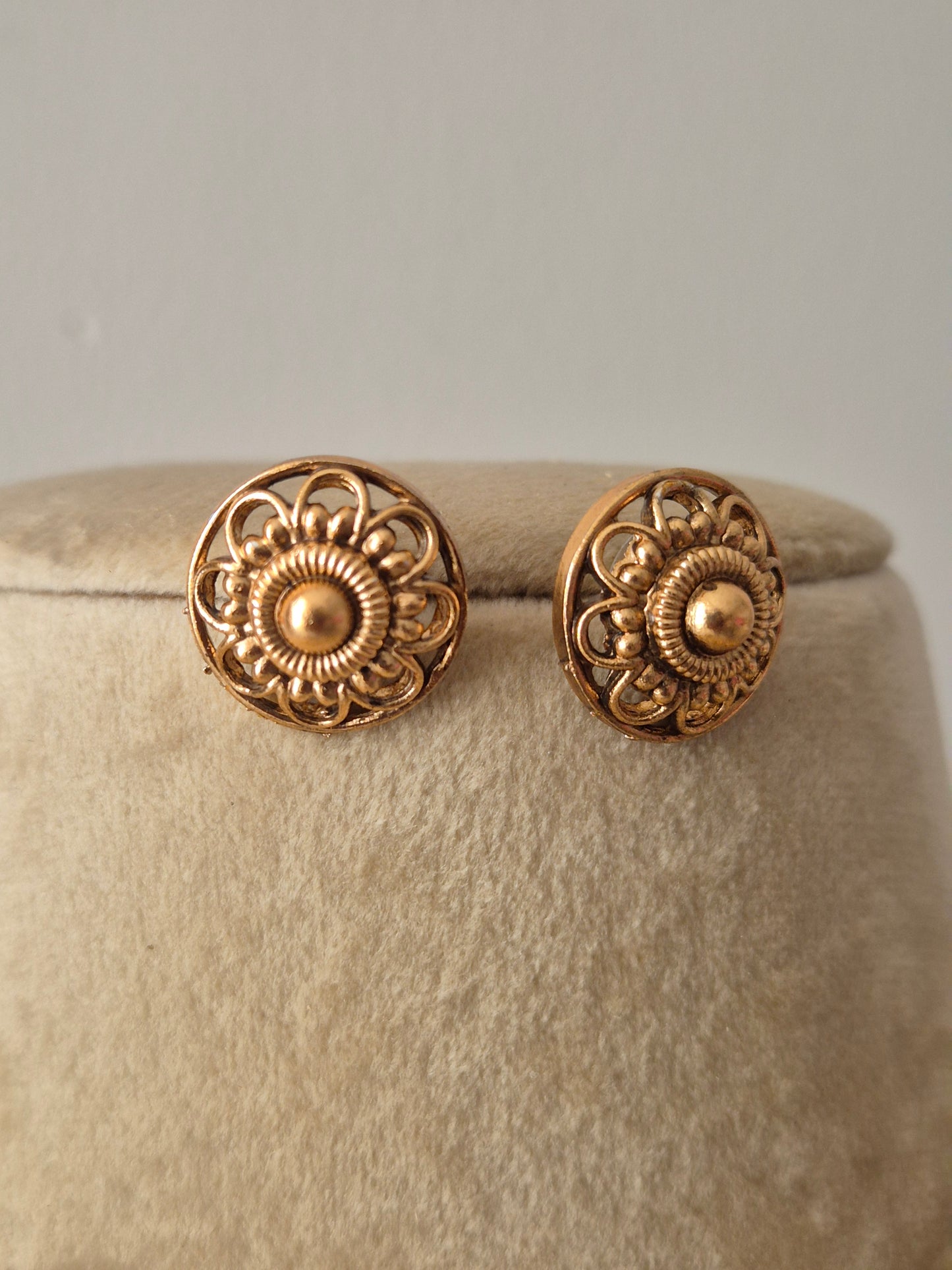 Gold-toned stud earrings with intricate floral engravings by naitri.in