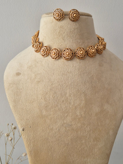 Necklace Set featuring a gold-toned choker with embossed circular floral motifs and matching round stud earrings by naitri.in
