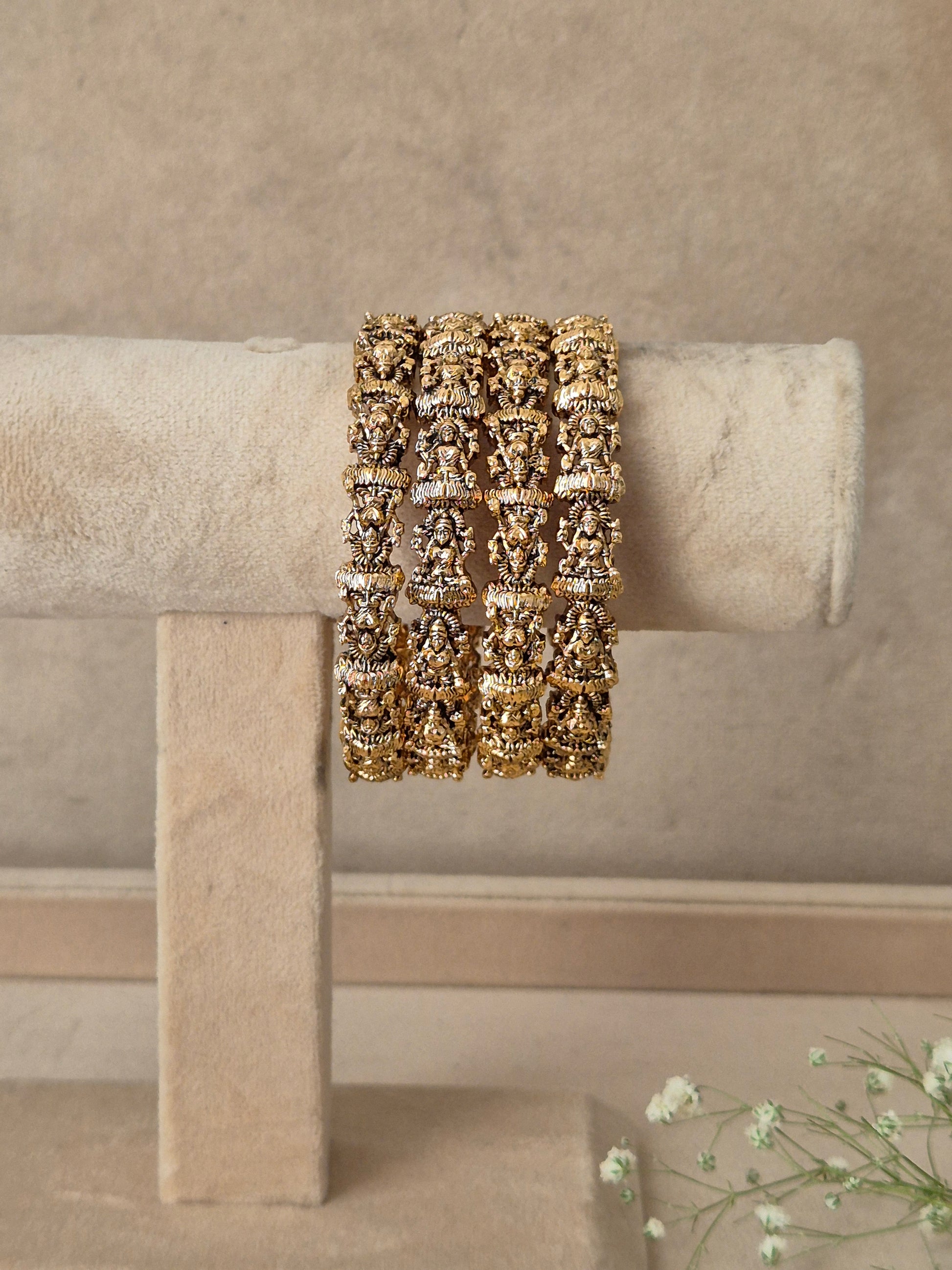 A wide gold cuff bracelet with intricate floral and scrollwork patterns, by naitri.in