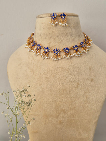Antique gold choker necklace with blue lotus motifs and hanging pearl clusters, with matching earrings by naitri.in