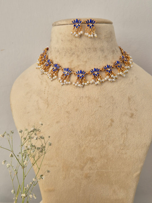 Antique gold choker necklace with blue lotus motifs and hanging pearl clusters, with matching earrings by naitri.in